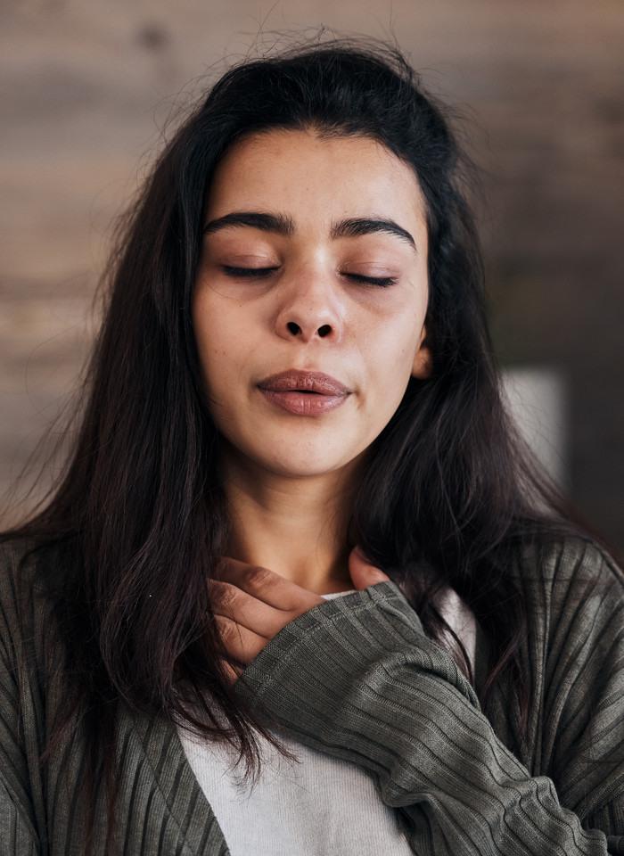 Person with hand over heart, eyes closed